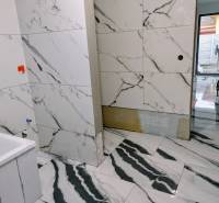 A bathroom in a family house with marble walls and flooring.