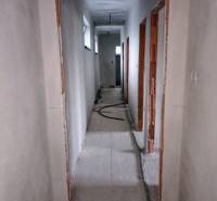 A hallway in a family house with unfinished electrical wiring and bare walls.