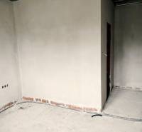 An unfinished interior in a family house with plastered walls and electrical installation preparation.