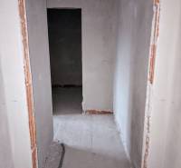A narrow corridor in an unfinished family house with exposed wiring on the floor.