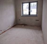 An unfinished room with new plaster and a large window in a family house.