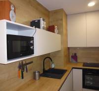 A kitchen in a 2-room apartment with wood decor, equipped with appliances and storage space.