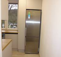 A kitchen with a wood-patterned floor and a refrigerator in a 2-room apartment.