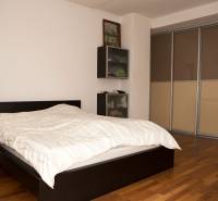 Bedroom in a family house with a bed and a wardrobe, floor with wooden decor.