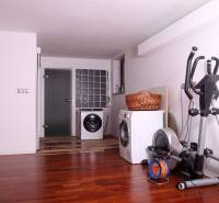 A family house with a wooden decor floor, a washing machine, a dryer, and an exercise machine.