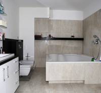 A bathroom with a large bathtub and light tiles in a family house.
