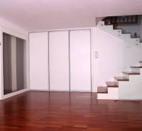 Interior of a family house with a wooden decor floor and a staircase with glass railing.