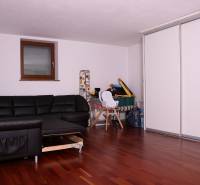 A family house with a black sofa, white cabinets, and a wooden decor floor.