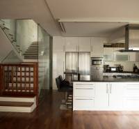 A kitchen in a family house with a wooden decor floor and glass staircase railing.