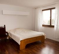A bedroom in a family house with a bed, an armchair, and a wooden decor floor.