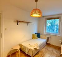 A room in a 3-room apartment with a bed, a table, and a floor with a wooden decor.