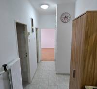 A hallway in a 3-room apartment with tiles, white walls, and wooden decor on the furniture.