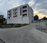 Apartment building in Piešťany on Banka street, next to the road with a sidewalk and railing.