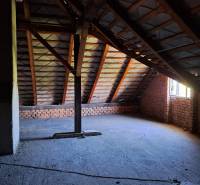 Attic in a family house with exposed bricks and the underlying roof structure.