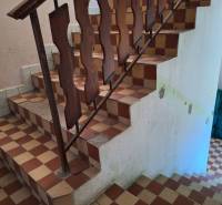 A staircase with a wooden railing in a family house with a tiled floor.