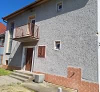 A family house in Šíd with a gray facade, a balcony, and concrete stairs in the exterior.