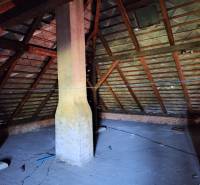 The attic of a family house in Šíd with wooden beams and a chimney.