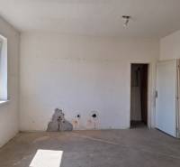 An empty room in a family house with a window and a damaged wall.