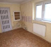 Room in a family house with light walls, a radiator, and a tiled floor.