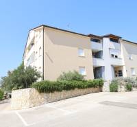 Recreational apartment in the town of Vodice with greenery, stone wall, and parking spaces.