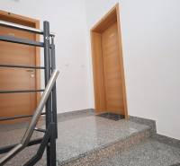 A staircase with a metal railing and wooden doors in a holiday apartment.
