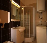 Compact bathroom with a corner shower and sink in a holiday apartment.