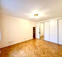 A bright room in a 4-room apartment with a wood-patterned floor and a large wardrobe.