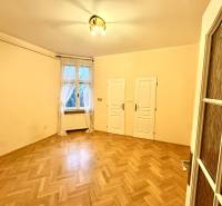 A room in a 4-room apartment with a wooden decor floor, a curtain, and two doors.