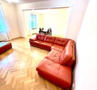 Living room of a 4-room apartment with a red sofa and a wooden decor floor.