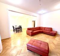 Living room in a four-room apartment with a red sofa and a wooden decor floor.