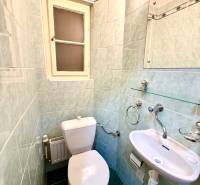 Bathroom in a 4-room apartment with a sink, toilet, and window with ceramic tiles.