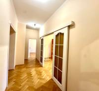 A hallway with sliding doors in a 4-room apartment and a floor with a wood decor.