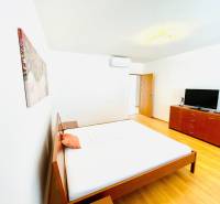 Bright bedroom in a 4-room apartment with wood-patterned flooring, a bed, and a dresser.