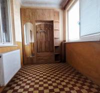 A hallway in a family house with tiles, a mirror, and a large window.