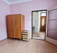 A room in a family house with pink walls, a wooden decor floor, and furniture.