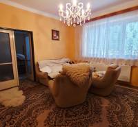 Living room in a family house with carpets, a chandelier, and comfortable armchairs.