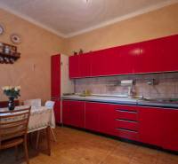 A kitchen in a family house with a red kitchen unit and a dining table, decorated with ceramic plates.