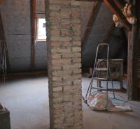 Attic of a family house with a brick pillar, steps, and a window in the roof section.