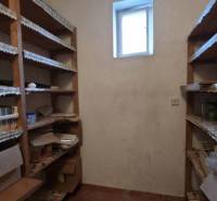 A pantry in a family house with shelves and a small window, suitable for storage.
