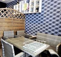 Wicker furniture in commercial spaces in front of a wall with a geometric pattern and a wooden screen.
