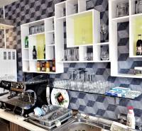 Interior of commercial space with a coffee machine, shelves, glasses, and drinks on the shelves.