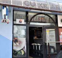 Commercial premises in Šaľa with a large window, wooden decor, and white chairs.