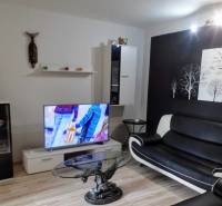 Living room with a black and white sofa, wood-patterned flooring, and a television.