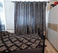 Bedroom in a 3-room apartment with a patterned curtain and a wardrobe, with a wooden decor floor.