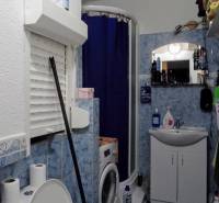 A bathroom in a 3-room apartment with blue tiles, a washing machine, and a shower corner.