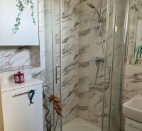 Compact bathroom with a shower and marble tiles in a 4-room apartment.