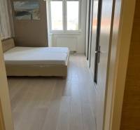 A bedroom with light furniture, a large window, and a floor with a wooden decor in a 4-room apartment.