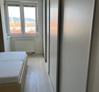 Bedroom in a 4-room apartment with a bed, wood-patterned floor, and a wardrobe.