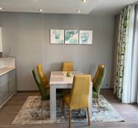Dining area in a 4-room apartment with colorful chairs and a wooden-patterned floor.