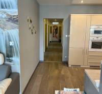 Living room in a 4-room apartment with a wooden decor floor and a kitchen unit.